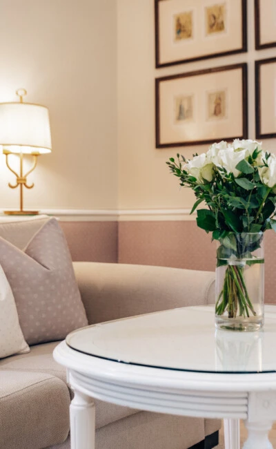 Gemütlicher Wohnbereich der Junior Suite im Hotel Sacher Salzburg mit Sofa, Couchtisch, frischen Blumen und klassischem Interieur