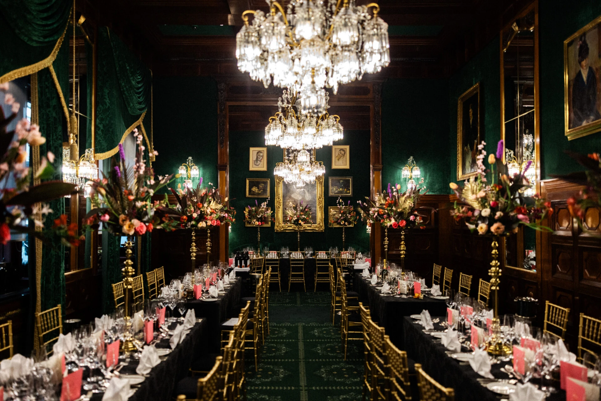 Festlich gedecktes Restaurant Grüne Bar im Hotel Sacher Wien mit langen Tafeln, Kristalllüstern, goldenen Stühlen und opulenten Blumenarrangements.