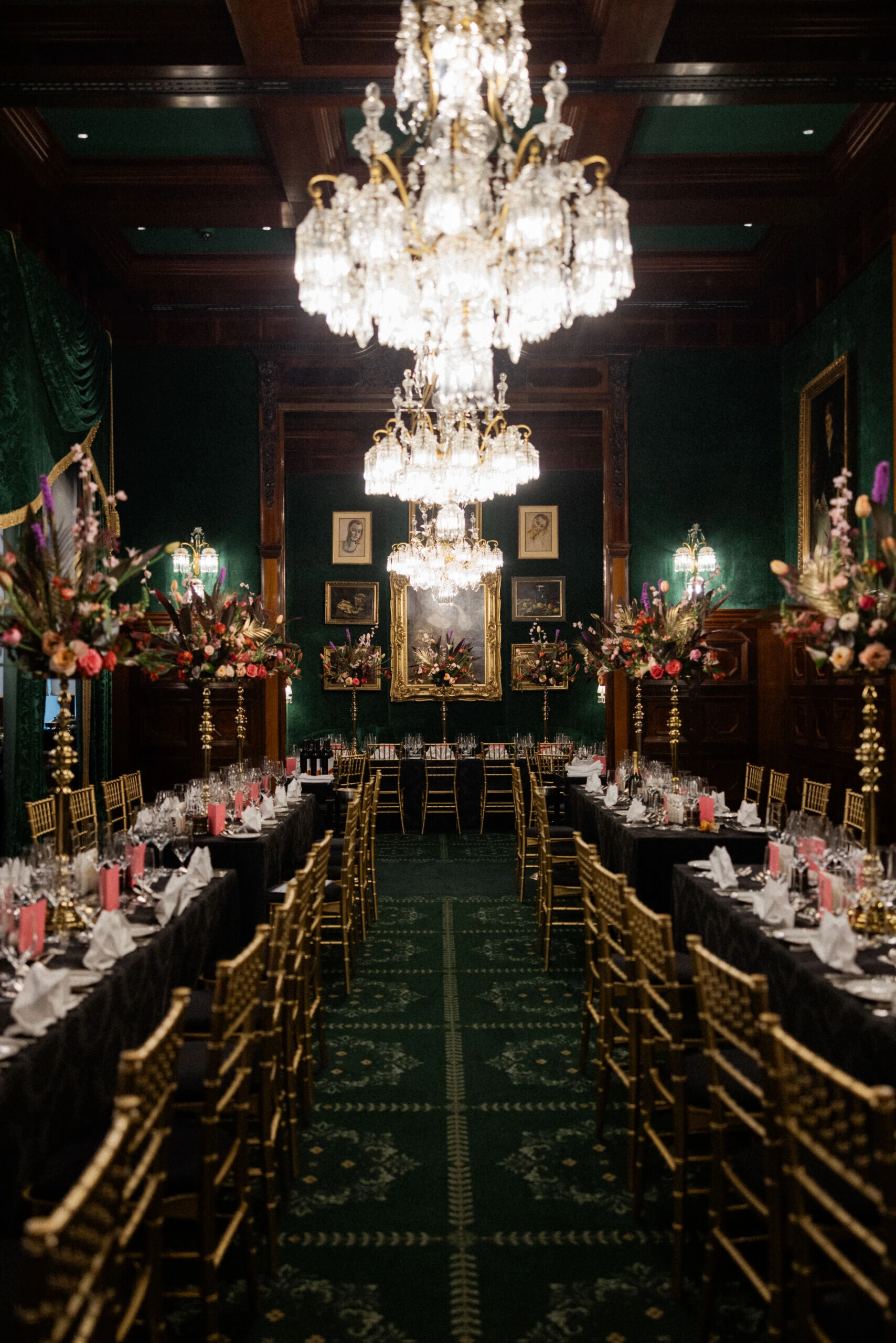 Festlich gedecktes Restaurant Grüne Bar im Hotel Sacher Wien mit langen Tafeln, Kristalllüstern, goldenen Stühlen und opulenten Blumenarrangements.