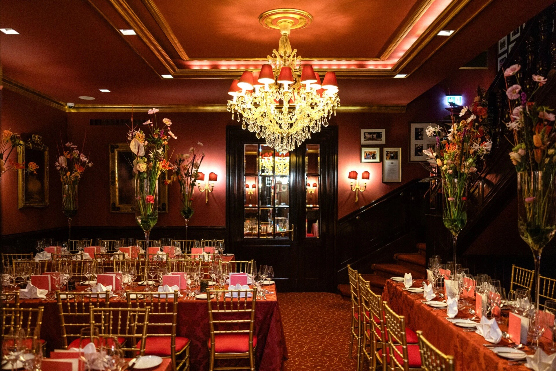 Festlich gedecktes Unteres Rendezvous im Hotel Sacher Wien mit Kronleuchter, Blumenarrangements und langen Tafeln.