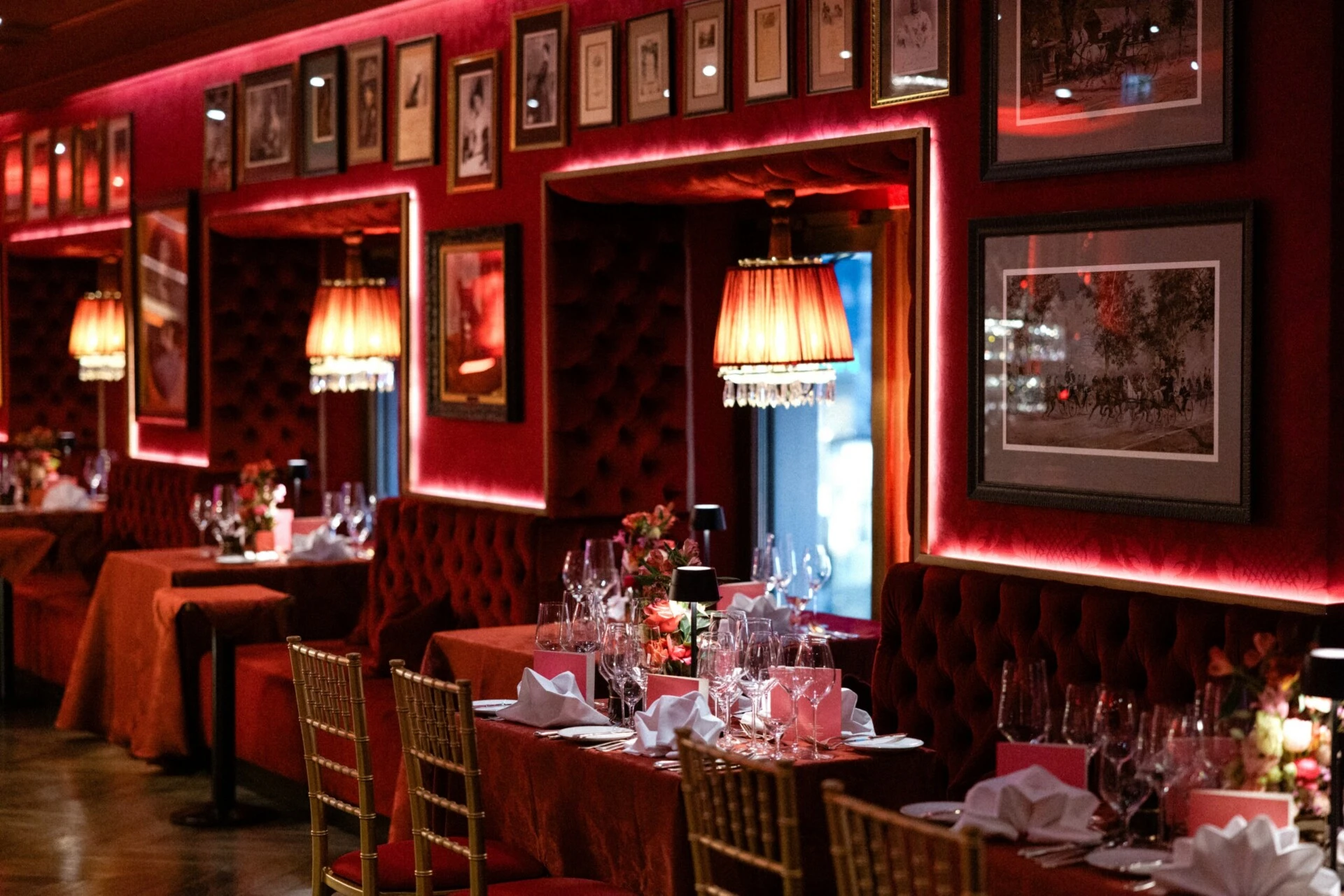 Festlich gedecktes Café Bel Étage im Hotel Sacher Wien mit roten Samtbänken, goldenen Stühlen und stimmungsvoller Beleuchtung.