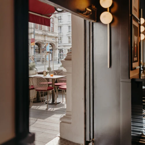 Blick vom Salon Sacher auf die angrenzende Terrasse mit Sitzplätzen im Freien.