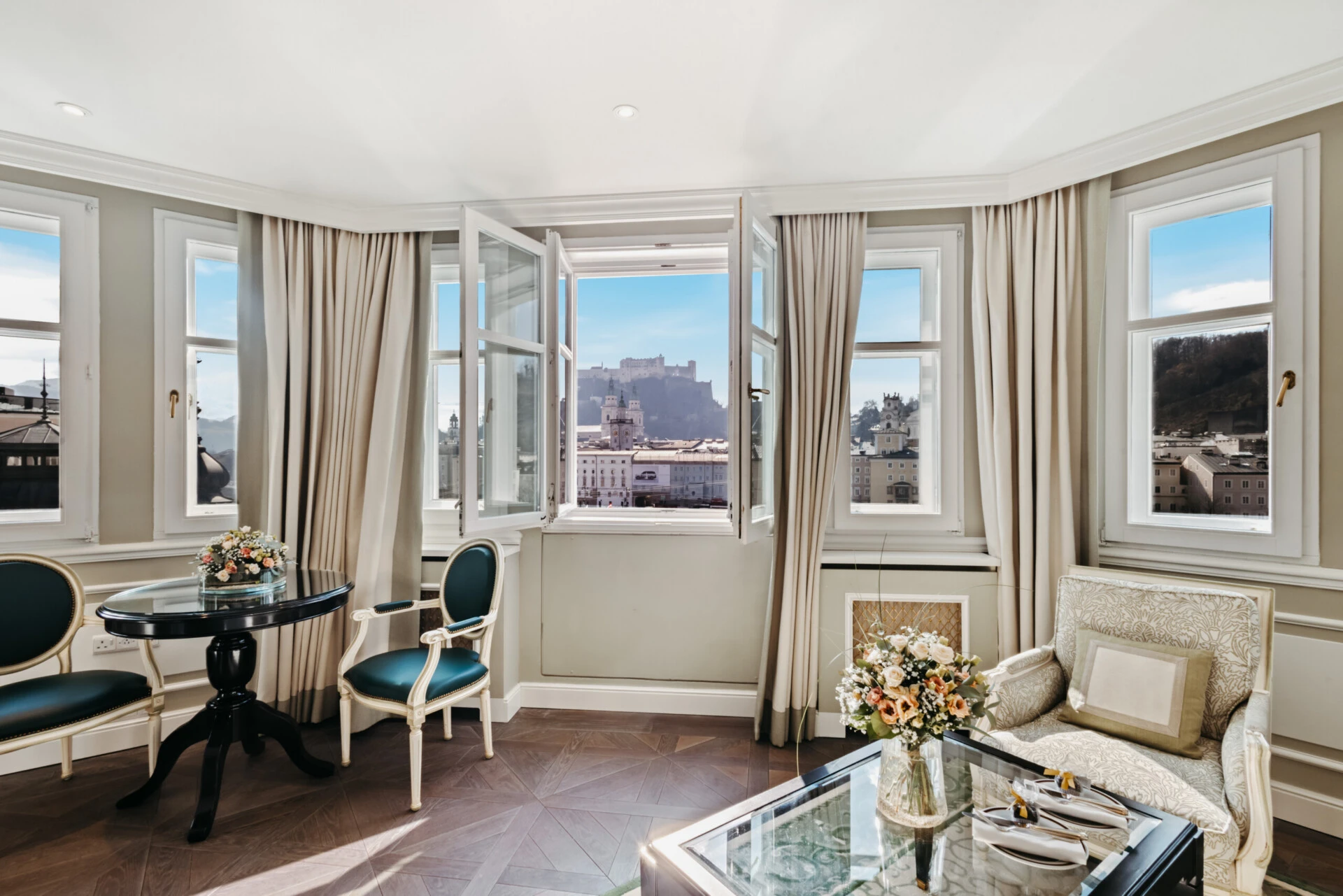 Wohnbereich der Signature Suite mit geöffnetem Fenster und Blick auf die Festung Hohensalzburg.
