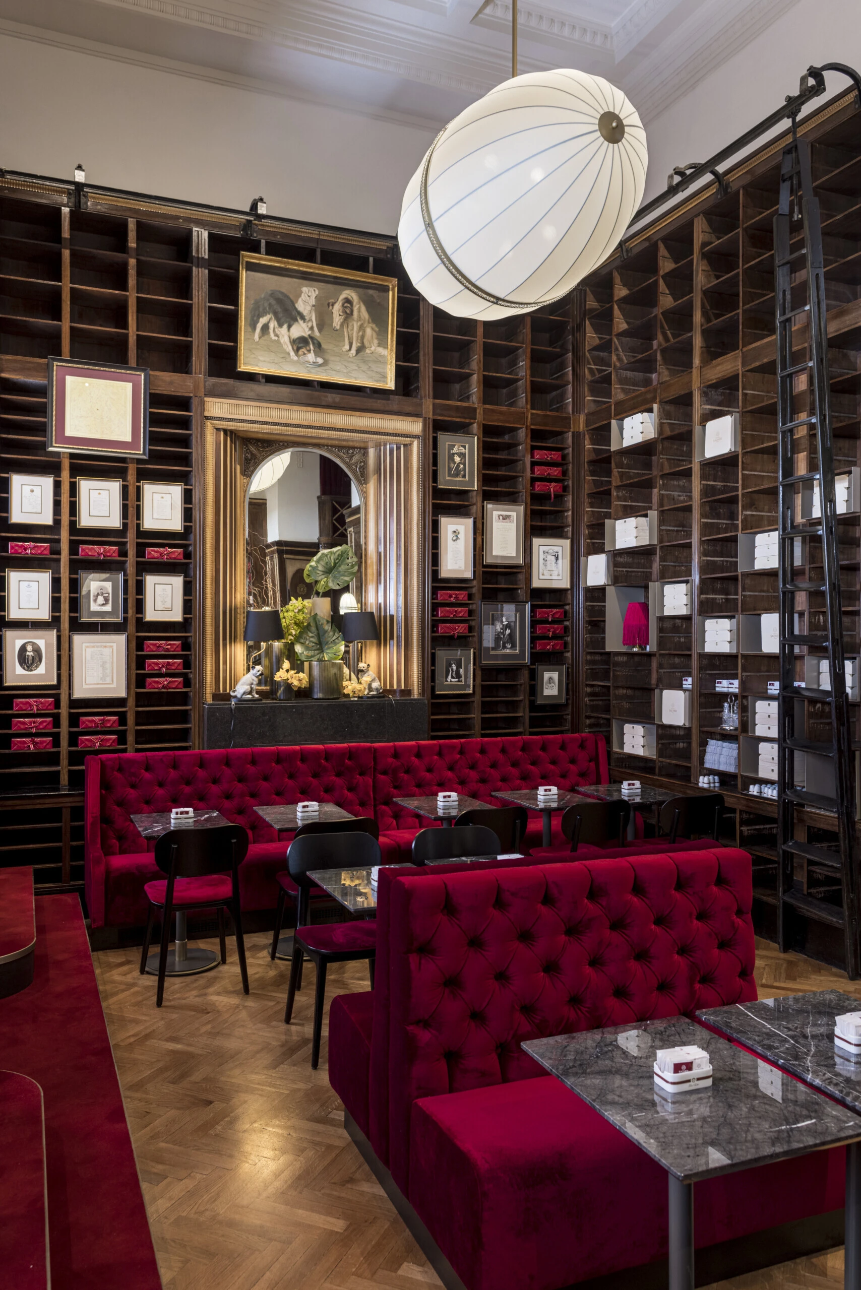 Gesamtansicht des Caffè Sacher Trieste mit roten Sitzbänken und eleganter Holzvertäfelung.