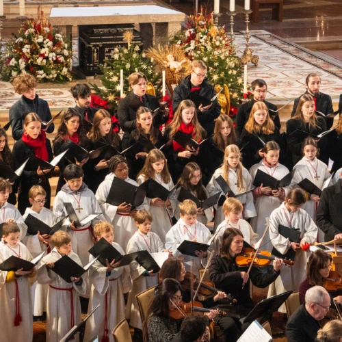 Kinder- und Jugendchor singt in einer festlich geschmückten Kirche, begleitet von einem Streichensemble.