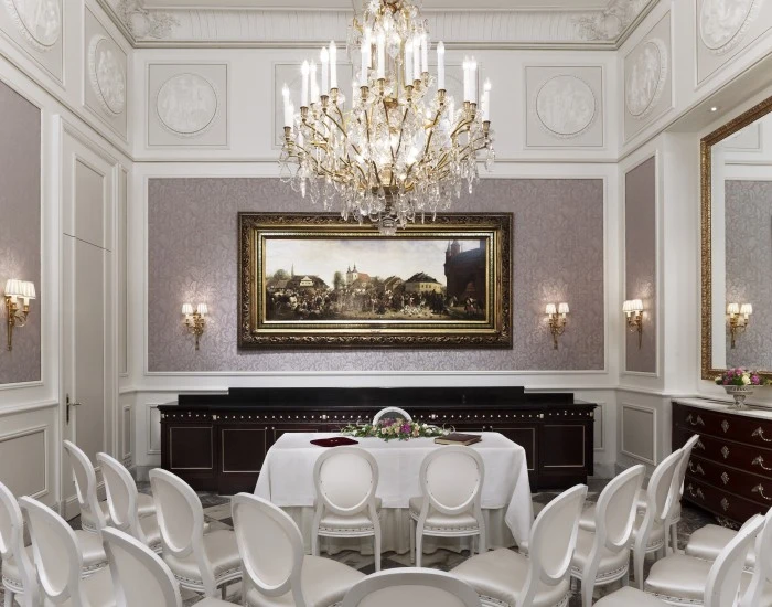Eleganter Salon im klassischen Stil mit Kristallluster, weißen Louis-Stühlen und dekorativen Wandreliefs – ideal für exklusive Empfänge oder Zeremonien.