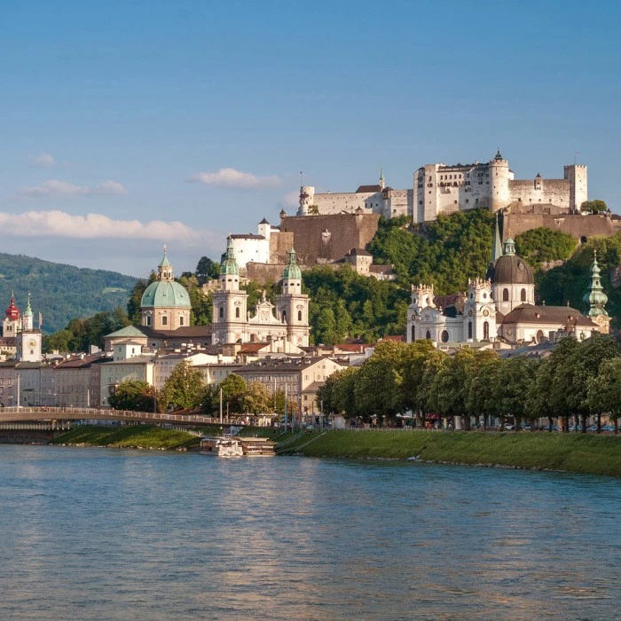 Blick über die Salzach auf die Altstadt von Salzburg mit der Festung Hohensalzburg im Hintergrund.