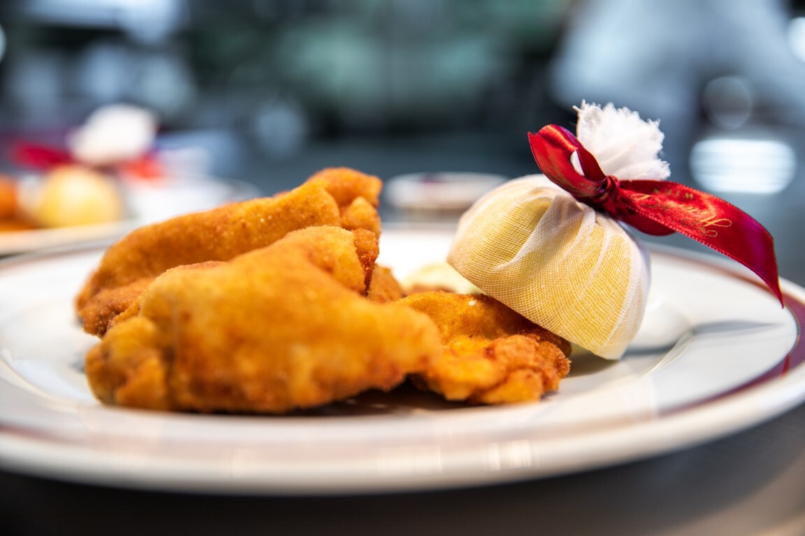 Knusprig paniertes Backhendl, appetitlich angerichtet auf einem weißen Porzellanteller mit feiner Bordüre.