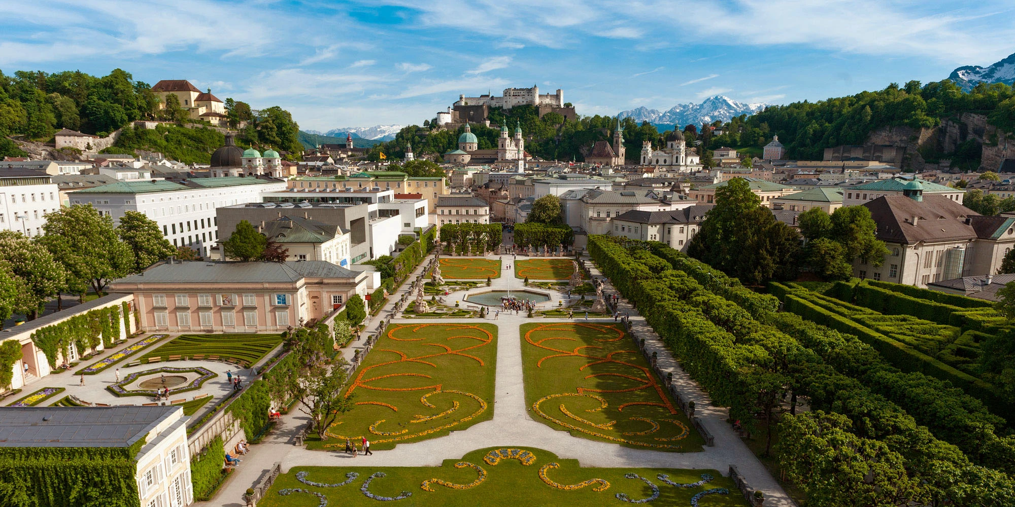 Mirabell Gardens bloom with vibrant flowers, framing a perfect view of Salzburg Cathedral and Hohensalzburg Fortress.