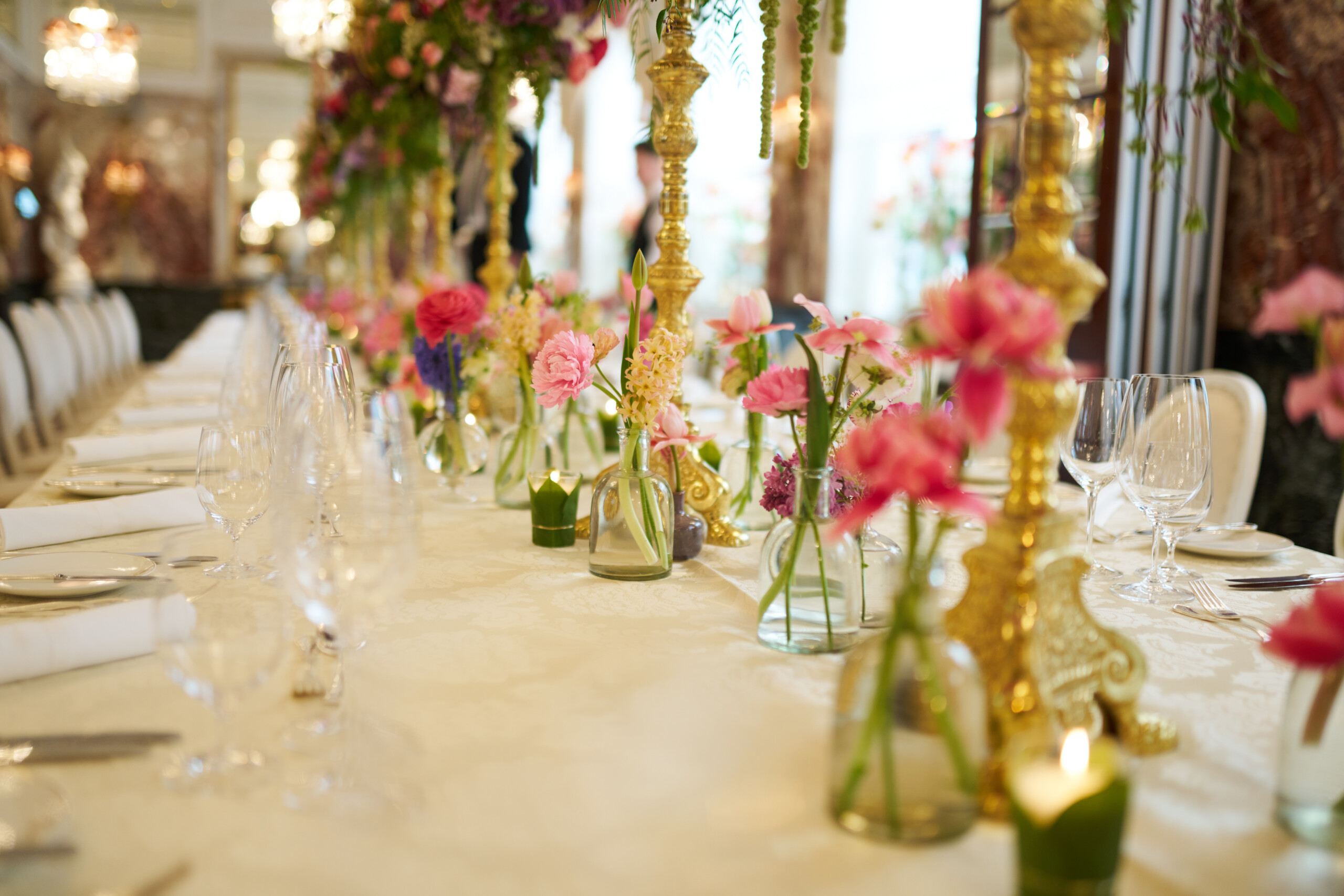 Luxurious wedding table at Hotel Sacher Vienna with colorful floral arrangements, gold candlesticks and elegant table setting for celebrations.
