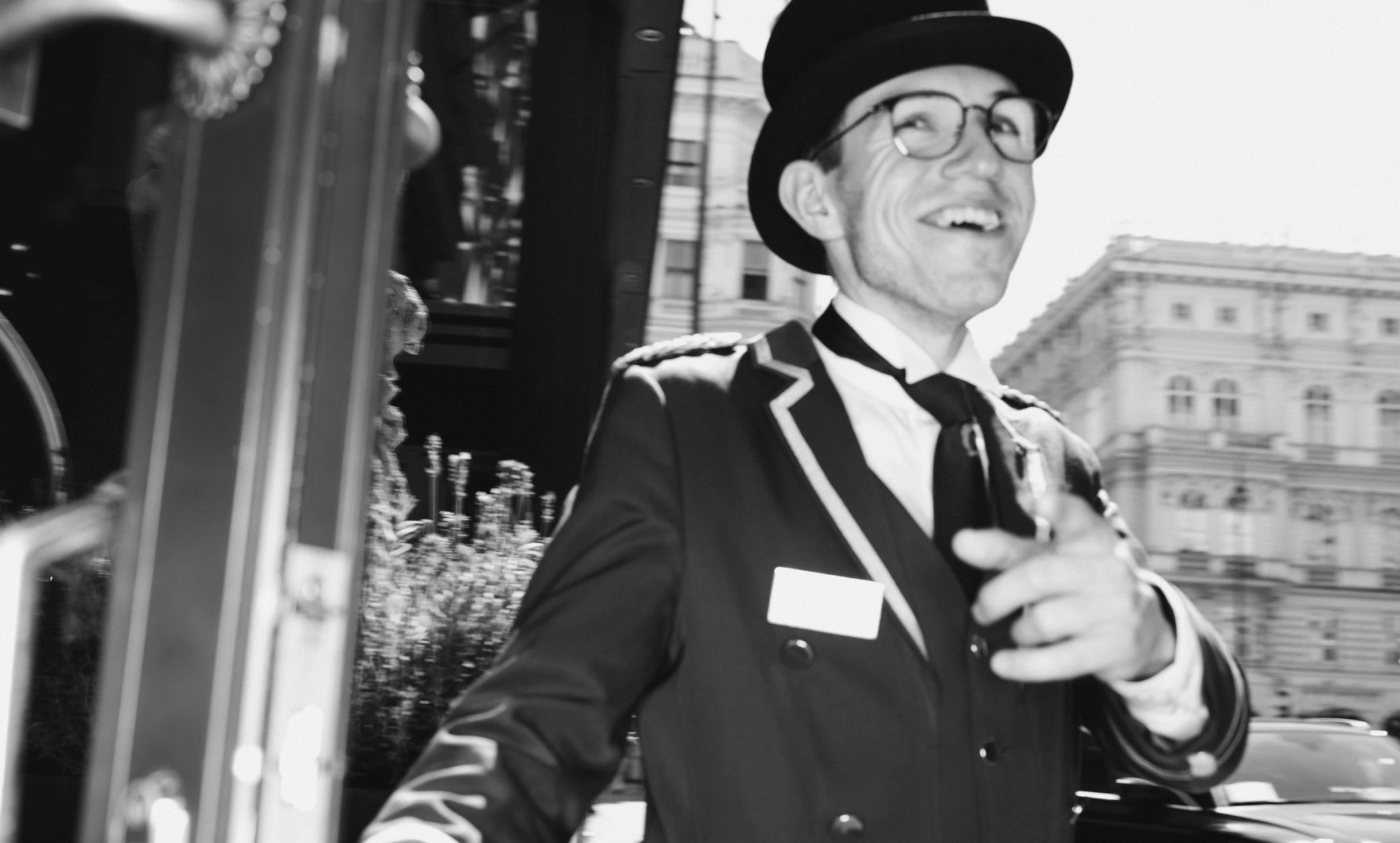 A cheerful doorman welcomes guests with a warm smile outside Hotel Sacher Wien, perfectly capturing the charm and elegance of the iconic Viennese landmark.