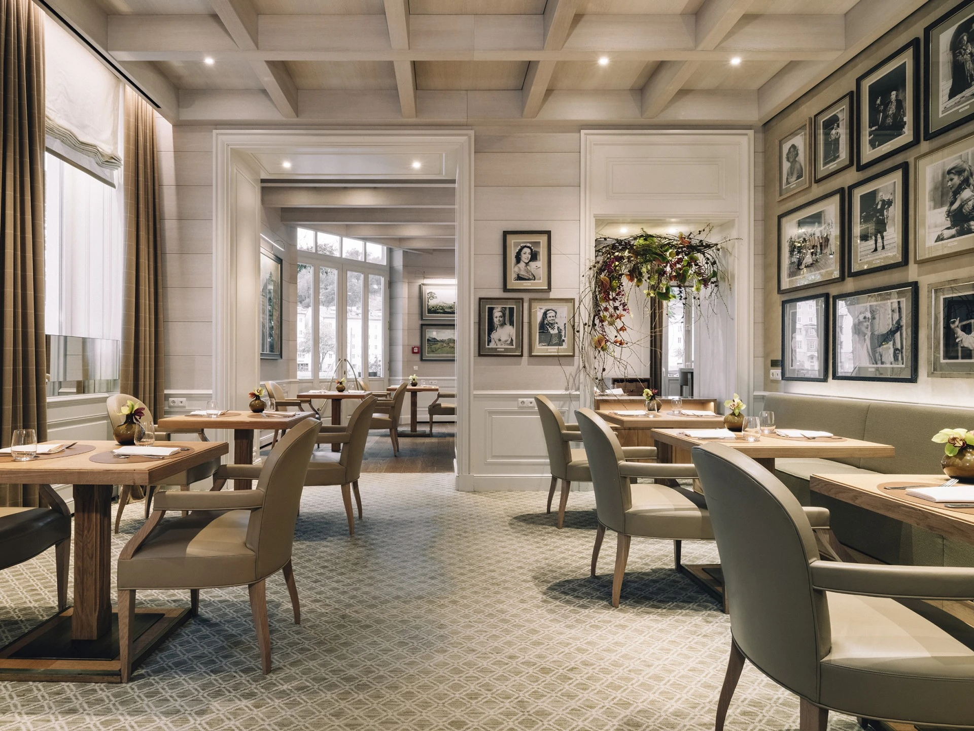 Bright and inviting dining area at Hotel Sacher Salzburg, featuring elegant, contemporary decor and framed photographs.