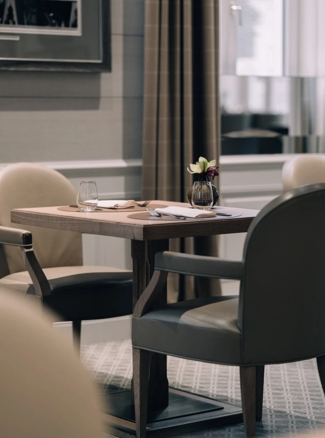 _HT28289 This image presents an intimate table setting at the Sacher Grill in Hotel Sacher Salzburg, with sleek wooden furniture, soft neutral tones, and a minimalist floral centerpiece creating a calm and sophisticated dining atmosphere.