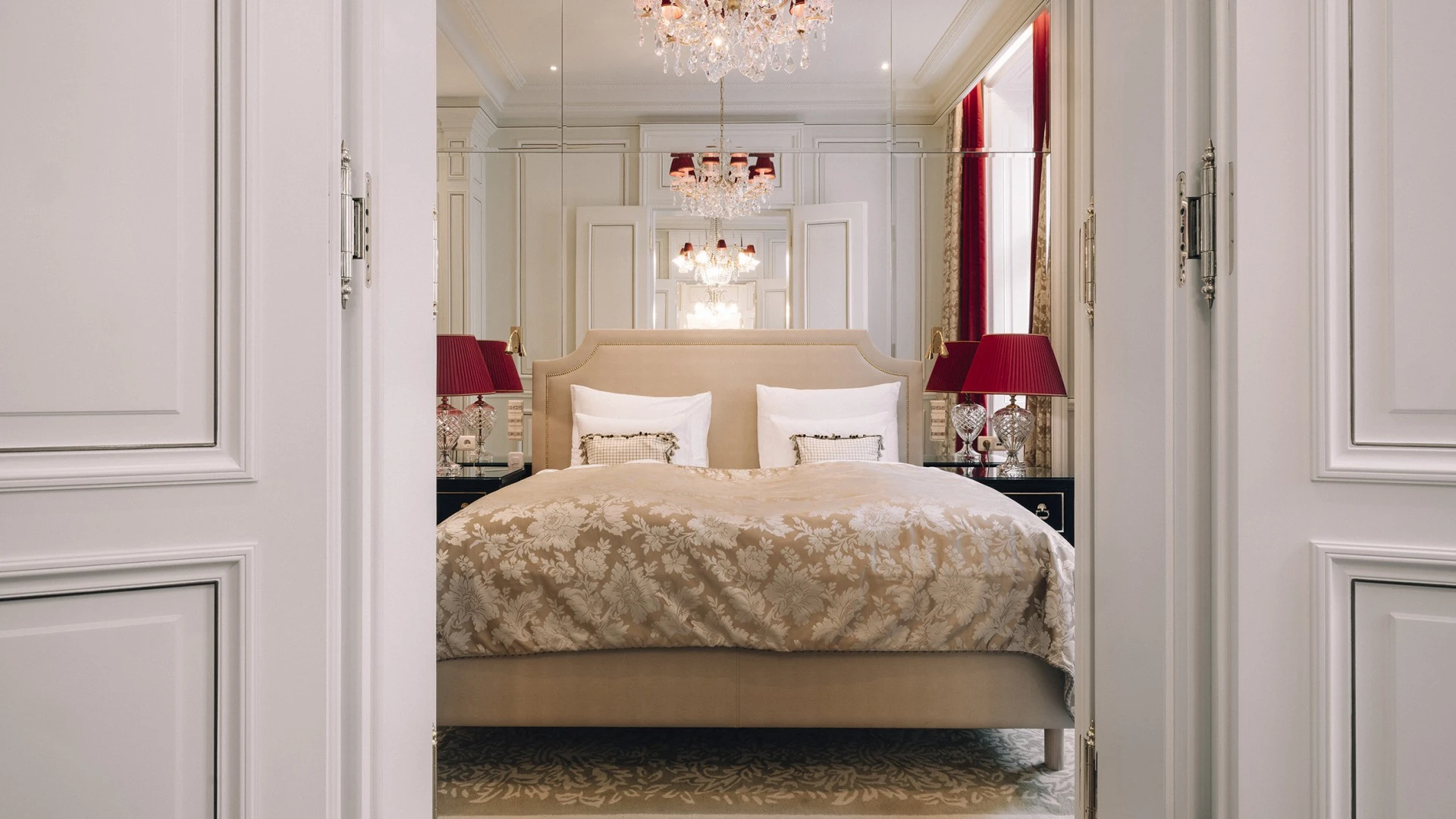 Bedroom in the Madame Butterfly Suite, left and right there is a bed stand with two elegant red lamps.