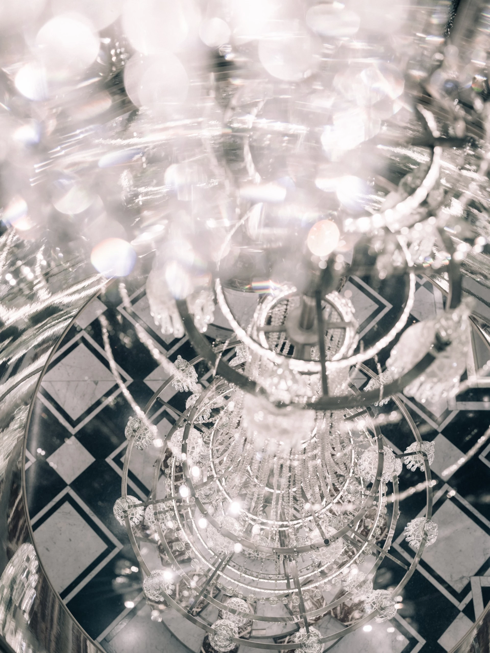 A dazzling spiral chandelier at the Confiserie casts sparkling reflections as it hangs above a polished black-and-white marble floor, creating an atmosphere of refined elegance.