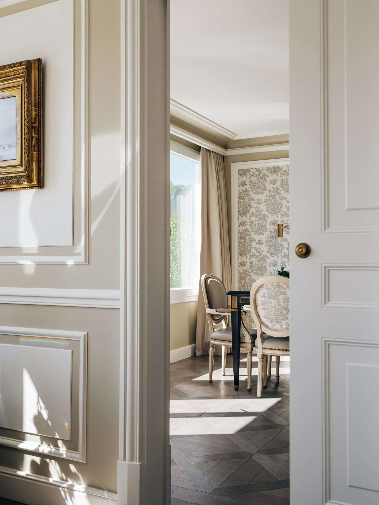 Soft morning light spills through a window into an elegant sitting room at Hotel Sacher Salzburg, highlighting the refined details of its classic interior design.