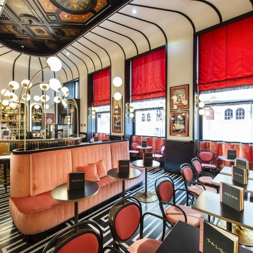 Salon Sacher's bold collaboration with Campari, where striking red accents, sleek black-and-white geometric flooring, and retro-chic decor create an atmosphere of stylish indulgence.