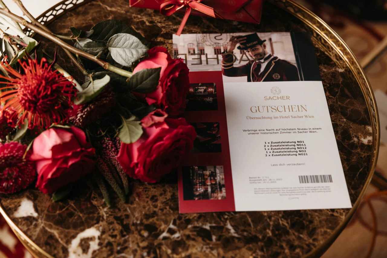 Voucher from Hotel Sacher on a table decorated with roses