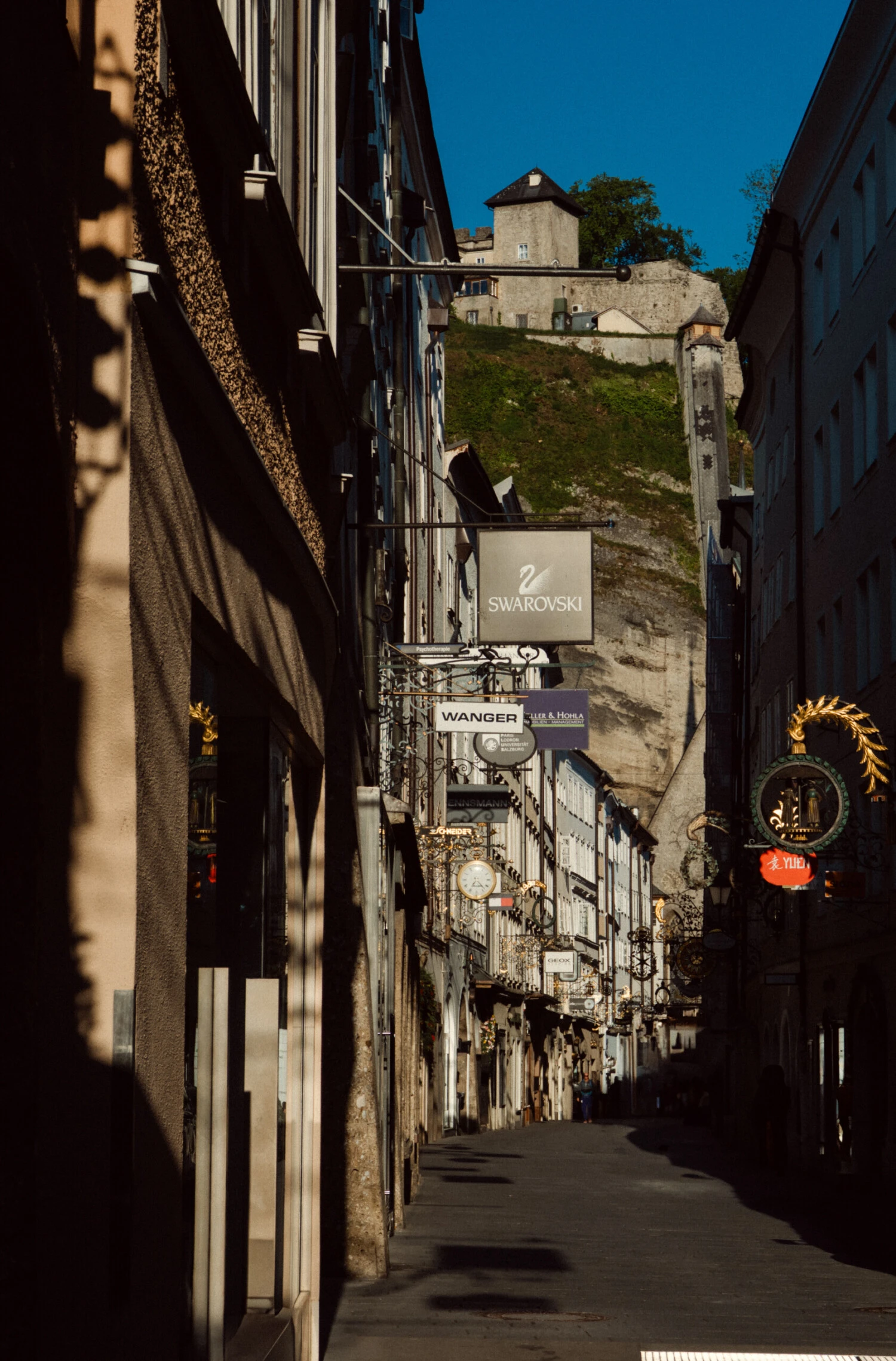 street in the old town of Salzburg with business shields hanging out of the stores