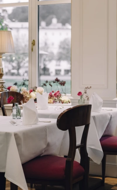 Cozy Salzachzimmer interior with flower-adorned windows, white tablecloths, and vintage table lamps