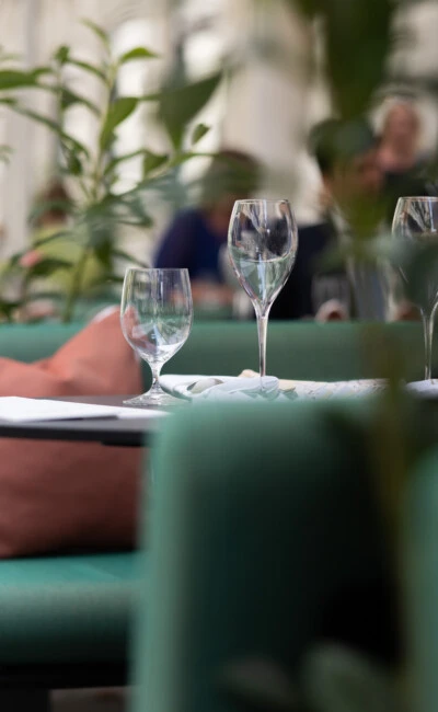 Close-up of an elegantly set table at the Sacher Summer Garden, with wine glasses, coral cushions, and lush greenery creating an intimate and refined outdoor ambiance.