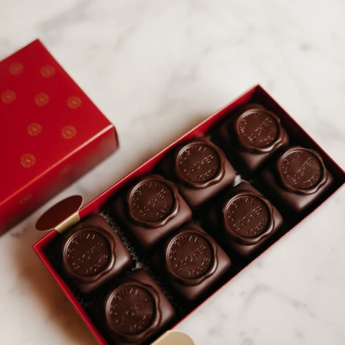 Red box with eight Sacher cubes inside, placed on a marble table