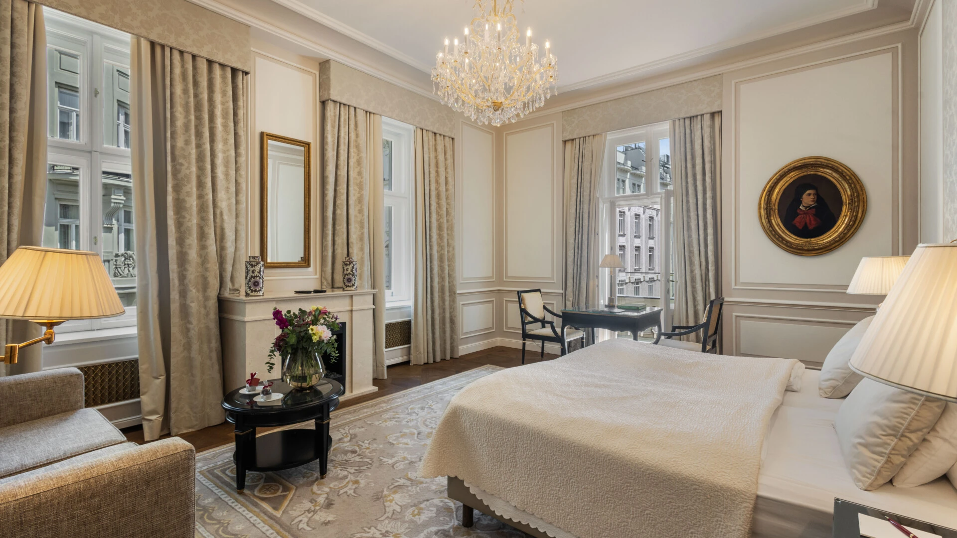 A beautiful hotel suite with classic decor, a comfortable bed, a writing desk, and a cozy seating area.