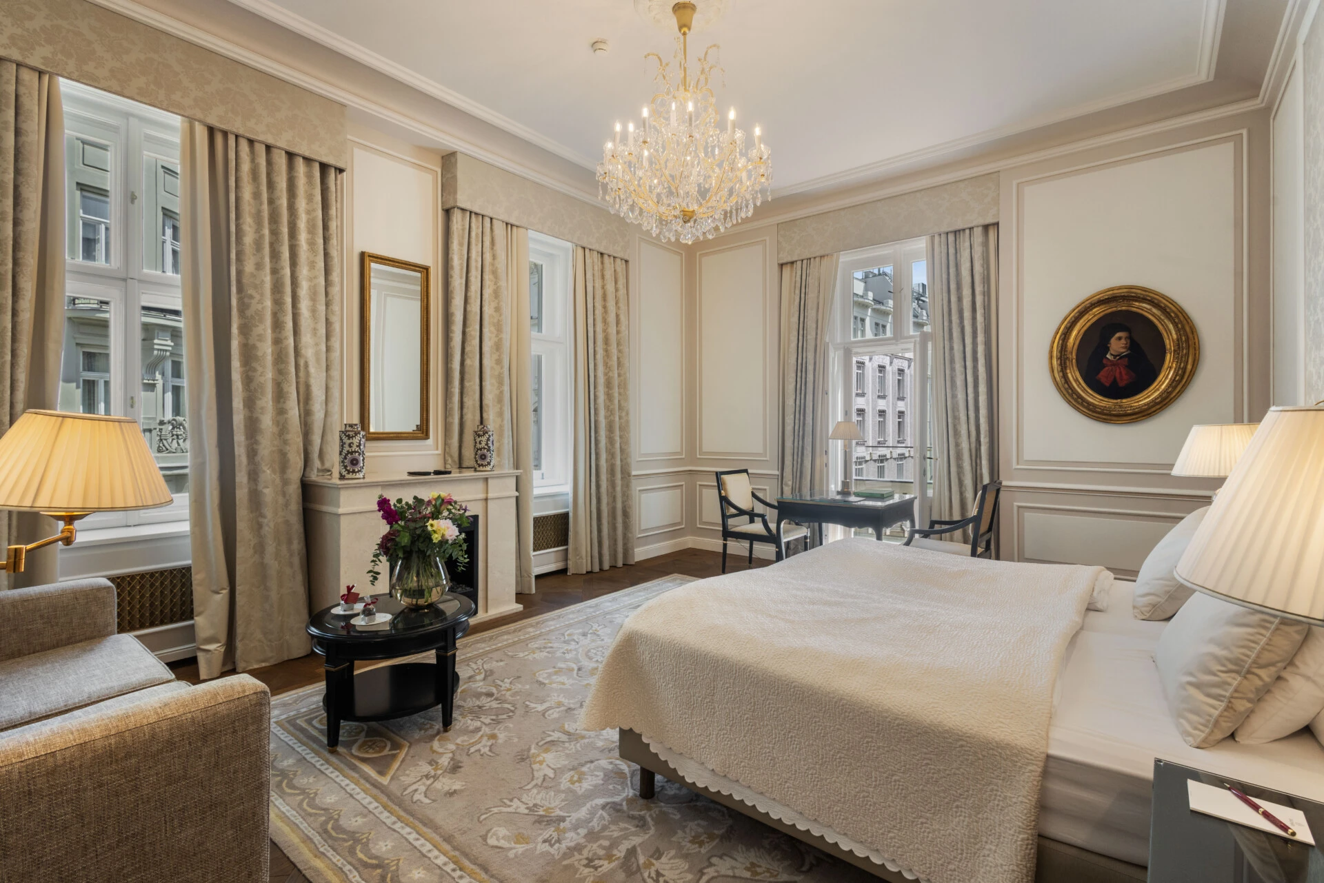 A beautiful hotel suite with classic decor, a comfortable bed, a writing desk, and a cozy seating area.