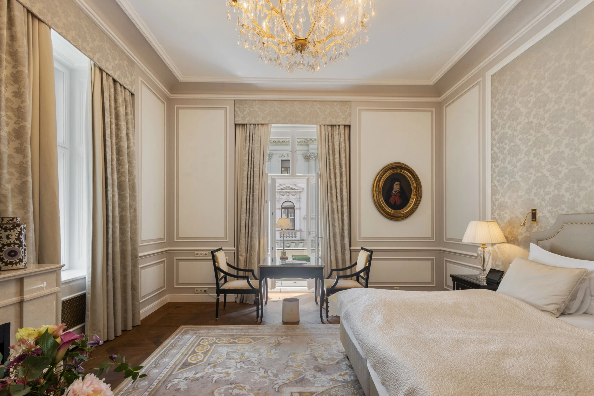 A beautiful hotel suite with classic decor, a comfortable bed, a writing desk, and a cozy seating area.