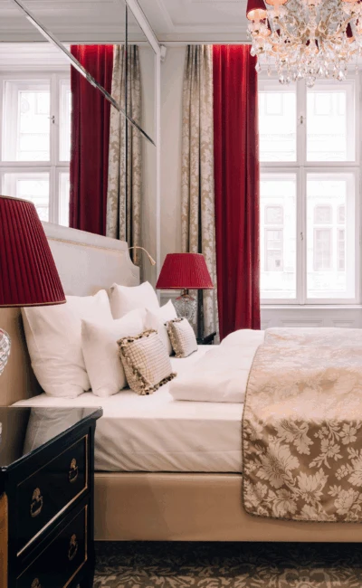 A luxurious hotel suite living room with a white sofa and a grand entrance to the bedroom.