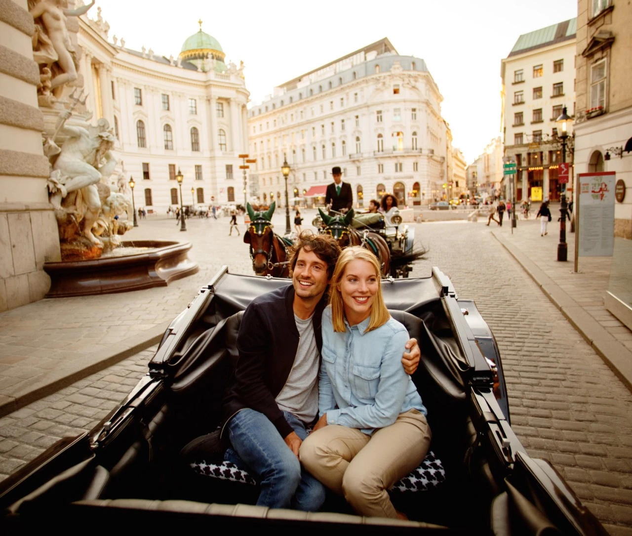 A couple enjoys a carriage ride through a historic square.