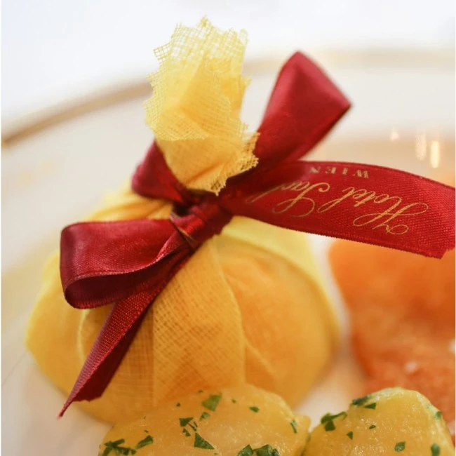 A delicately wrapped lemon with Hotel Sacher’s signature ribbon adds a refined touch to a classic Viennese meal.