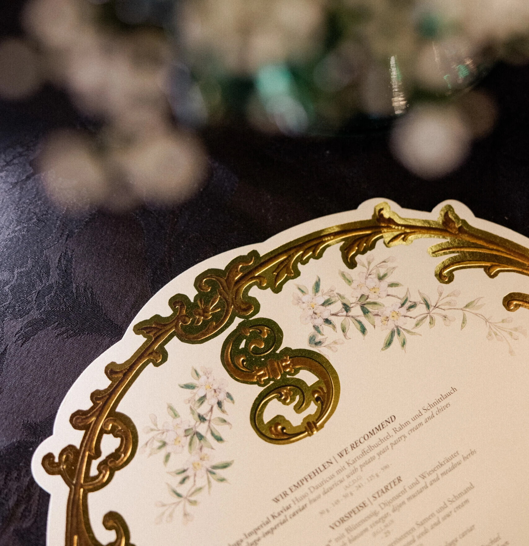 Close-up of a decorative menu card with golden ornaments on the table.