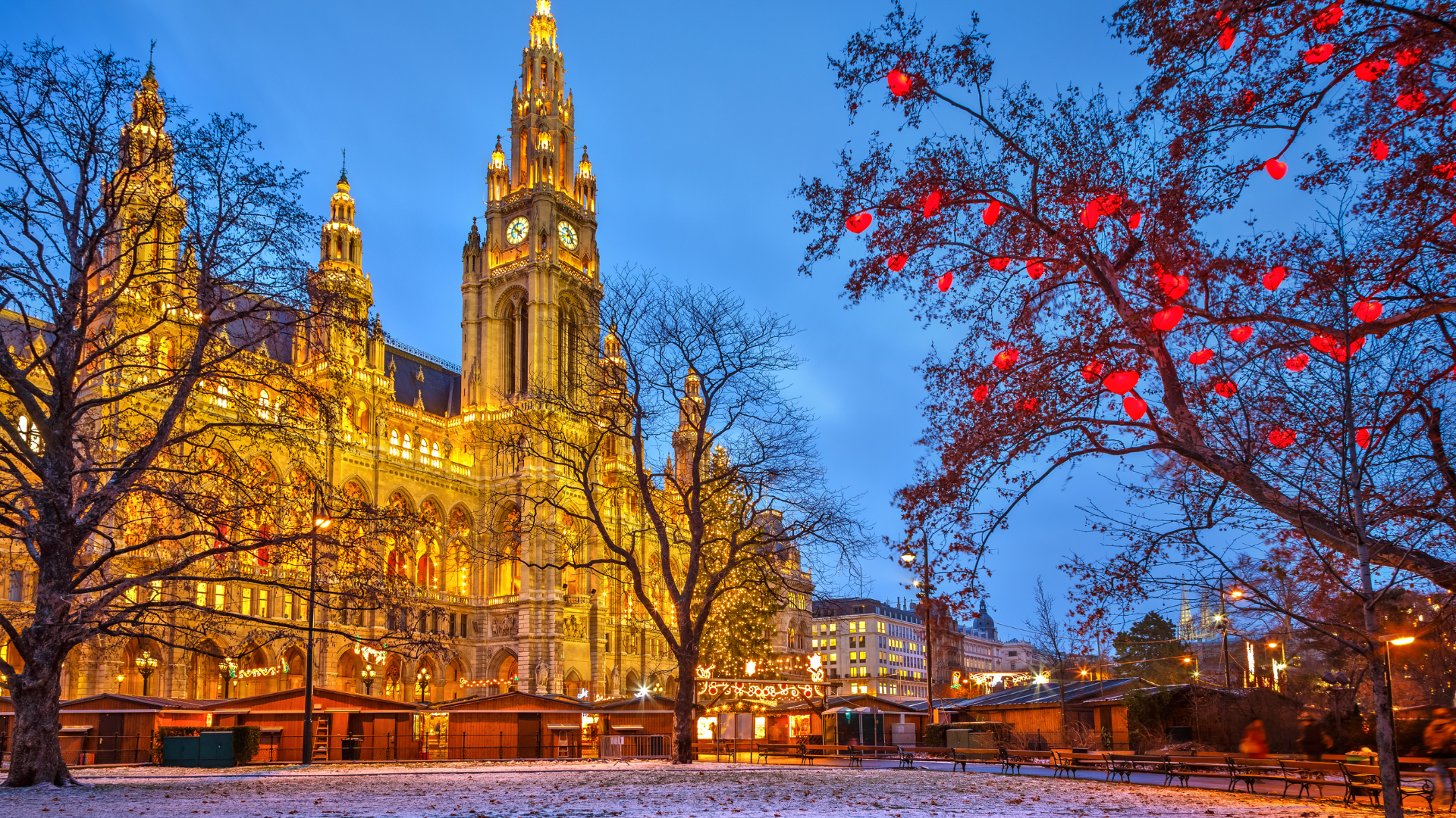 Vienna City Hall glowing with festive Christmas lights and market stalls at dusk