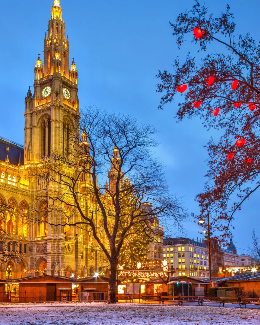 Vienna City Hall glowing with festive Christmas lights and market stalls at dusk