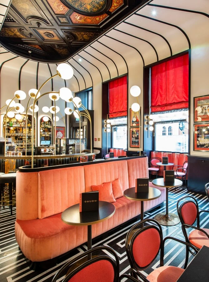 Salon Sacher's bold collaboration with Campari, where striking red accents, sleek black-and-white geometric flooring, and retro-chic decor create an atmosphere of stylish indulgence.