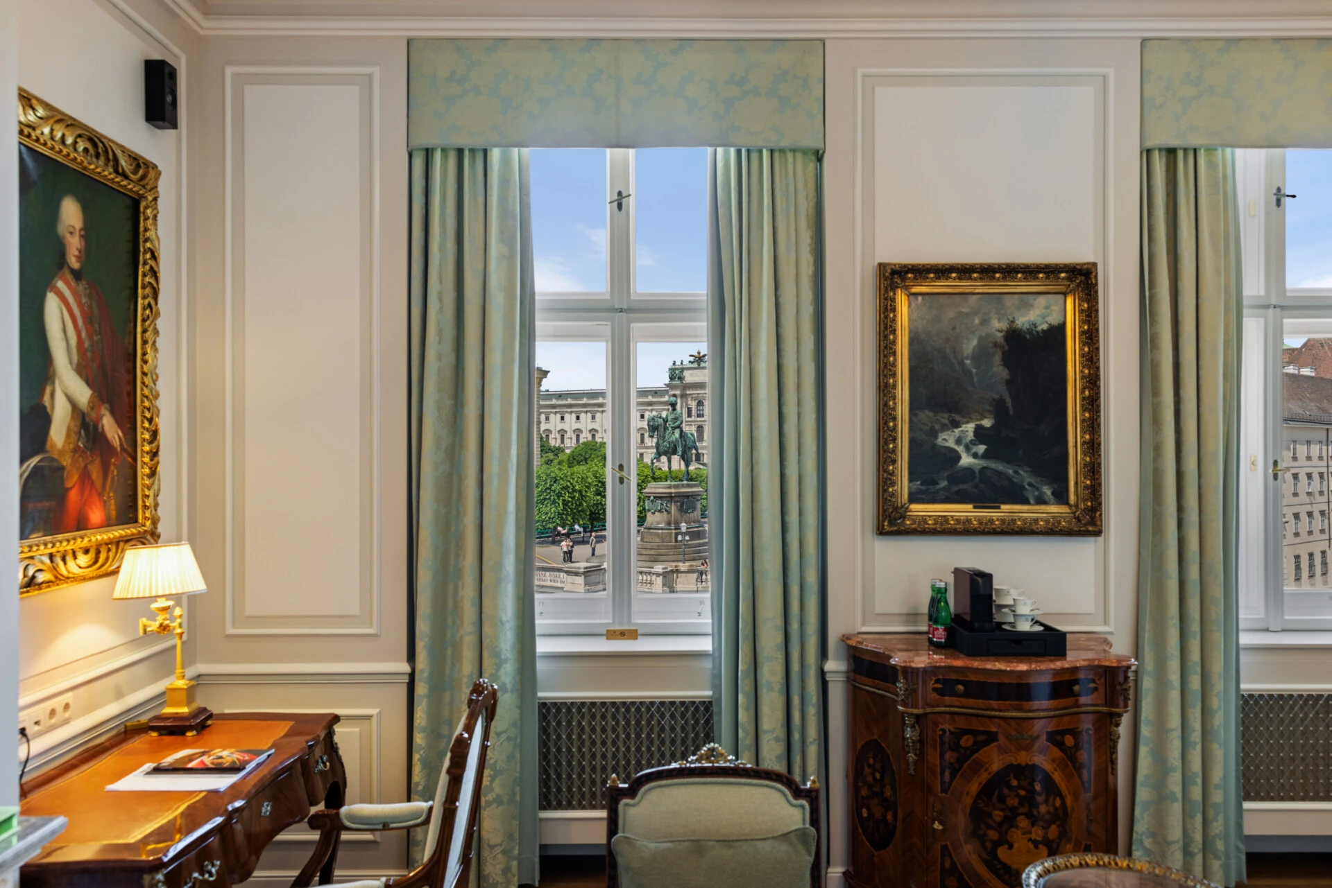 Classic guest room at Hotel Sacher Vienna with historic paintings, writing desk, antique cabinet and window view of central Vienna.
