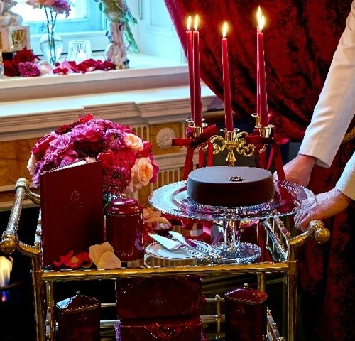 Original Sacher-Torte served on a silver trolley at Hotel Sacher Vienna with candles, flowers and elegant classic interior.