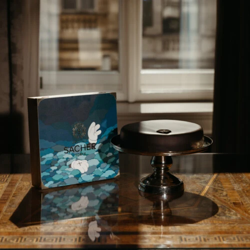 Original Sacher-Torte with artistic gift box at Hotel Sacher Vienna, displayed on an ornate console table in a classic luxury interior.