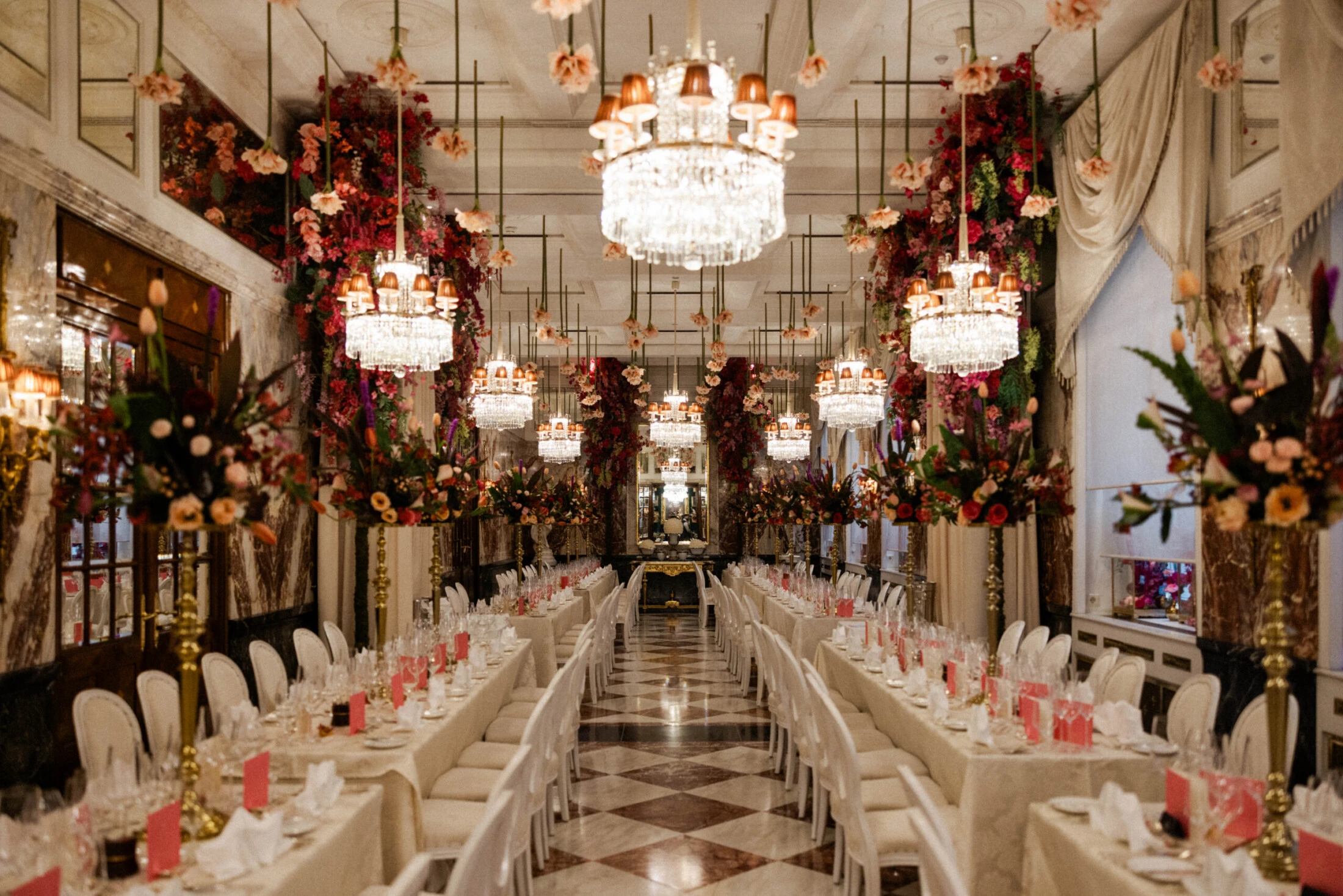 Elegantly decorated event hall with long banquet tables, lavish floral arrangements, and crystal chandeliers at Hotel Sacher
