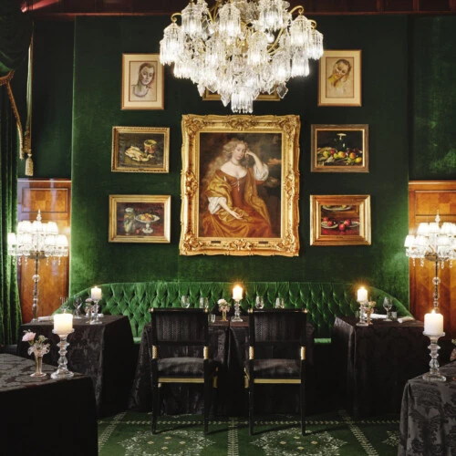 Restaurant Grüne Bar at Hotel Sacher Vienna with green velvet interior, chandeliers, candlelit tables and historic artwork for fine dining.