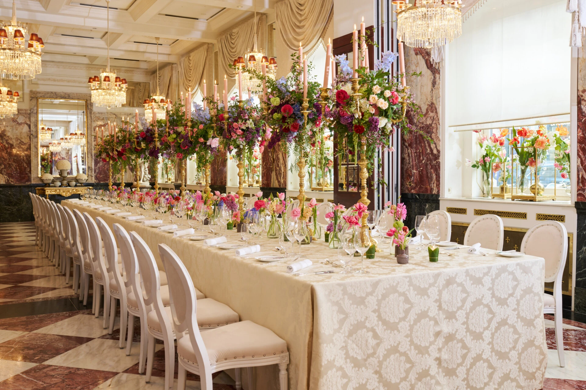 Luxurious wedding table at Hotel Sacher Vienna with colorful floral arrangements, gold candlesticks and elegant table setting for celebrations.