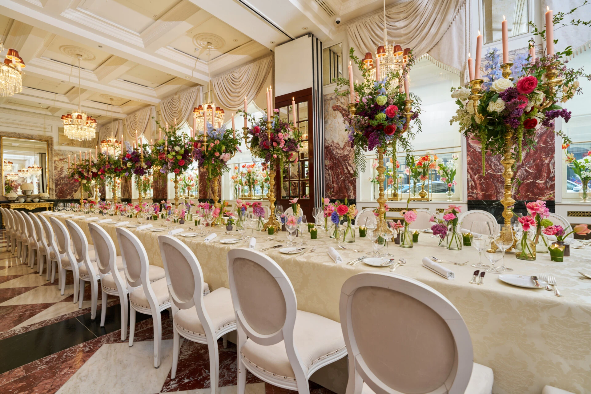 Luxurious wedding table at Hotel Sacher Vienna with colorful floral arrangements, gold candlesticks and elegant table setting for celebrations.