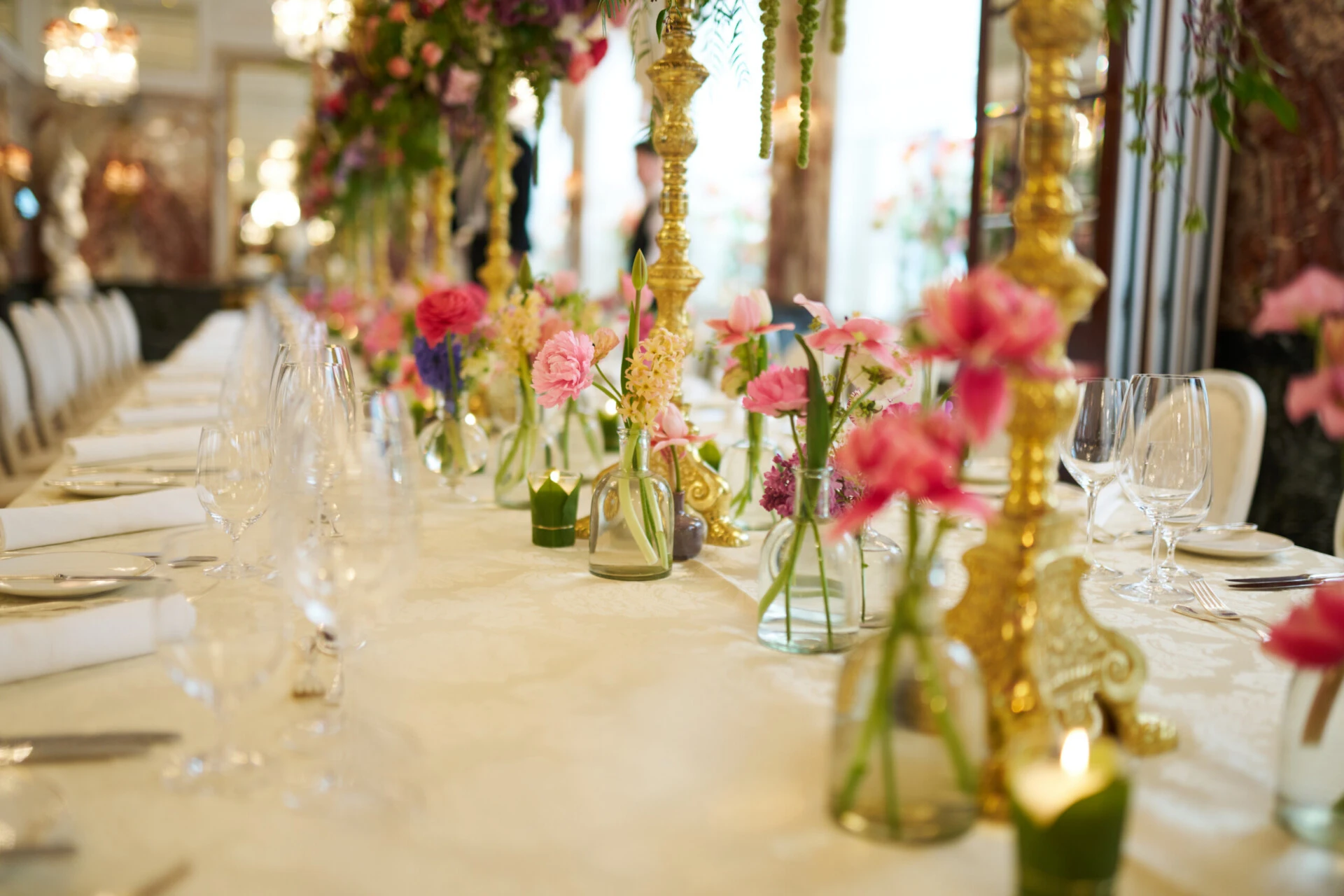 Luxurious wedding table at Hotel Sacher Vienna with colorful floral arrangements, gold candlesticks and elegant table setting for celebrations.