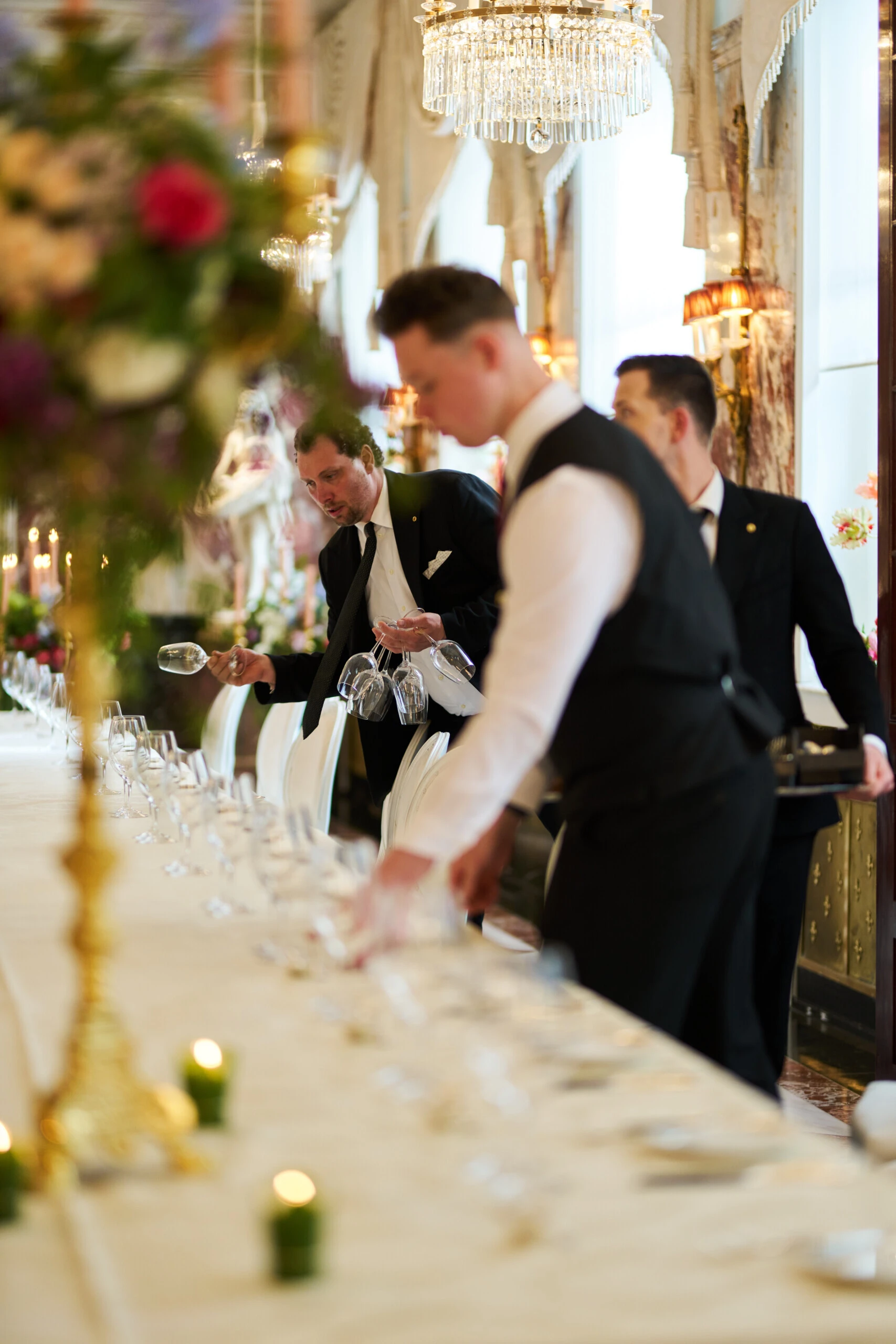 Sacher Vienna service team preparing an elegant wedding table with glassware, floral arrangements and candlelight in a luxury event room.