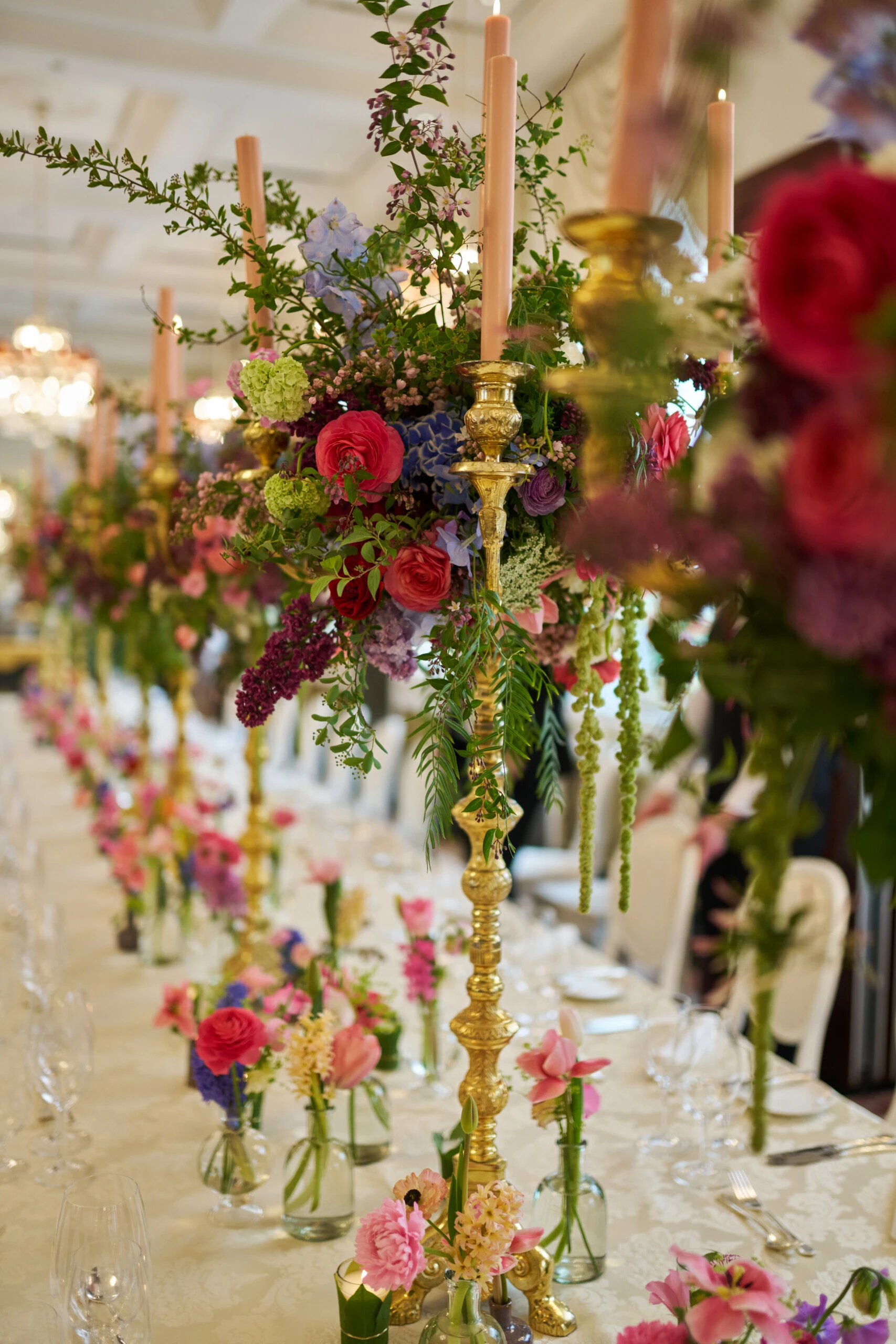 Luxurious wedding table at Hotel Sacher Vienna with colorful floral arrangements, gold candlesticks and elegant table setting for celebrations.