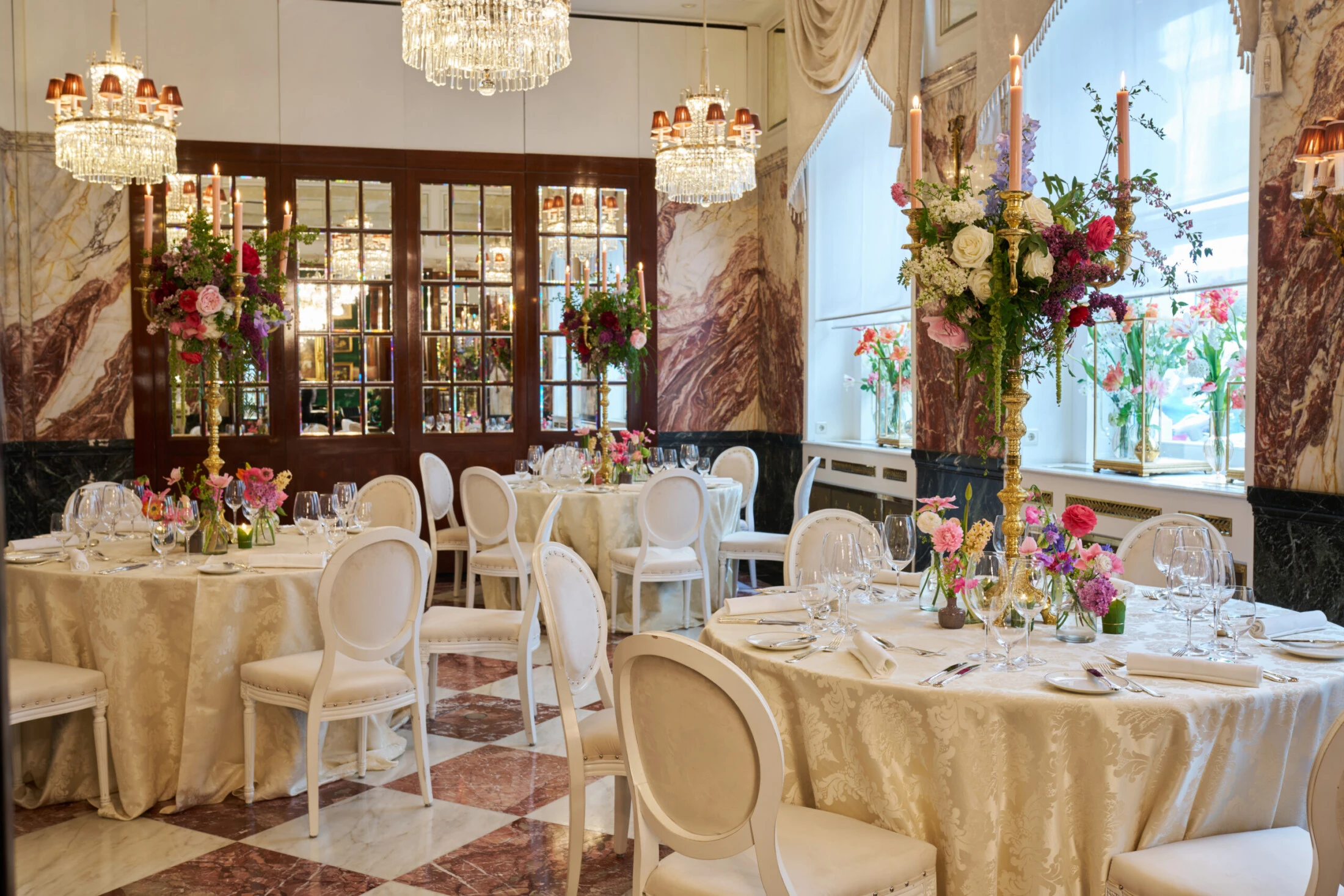Elegant event room at Hotel Sacher Vienna with chandelier lighting, round dining tables, floral arrangements and luxury interior for weddings and celebrations.