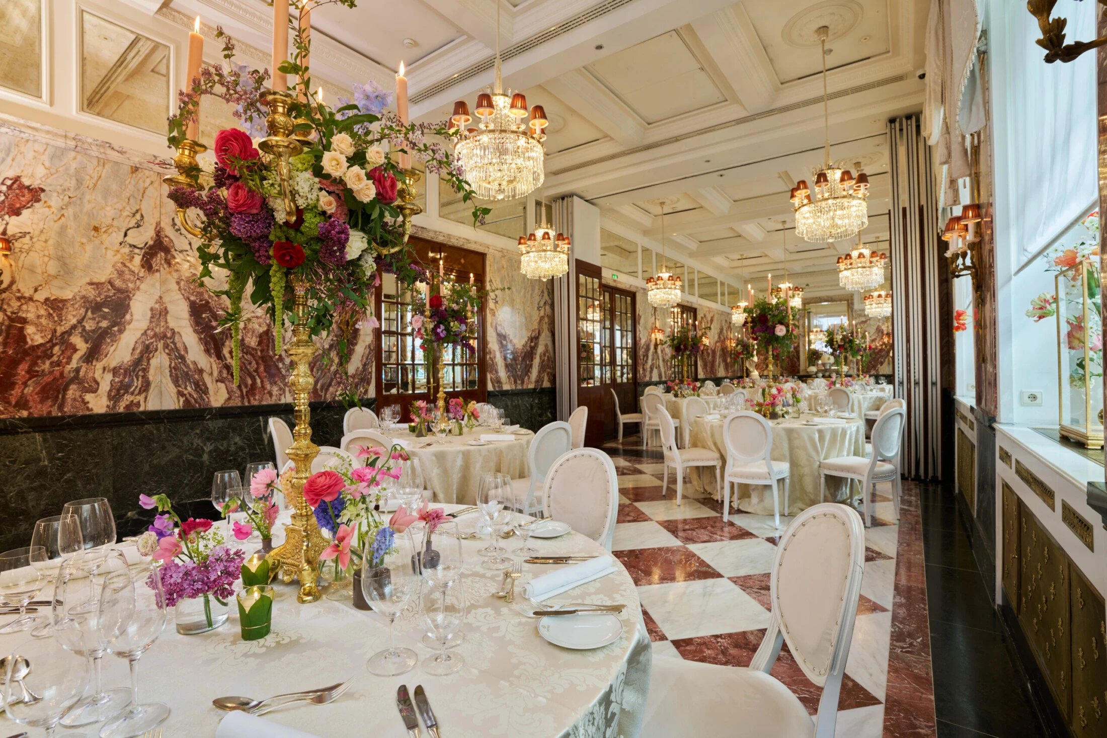 Elegant event room at Hotel Sacher Vienna with chandelier lighting, round dining tables, floral arrangements and luxury interior for weddings and celebrations.