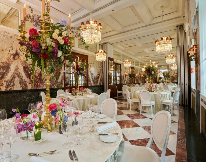 Elegant event room at Hotel Sacher Vienna with chandelier lighting, round dining tables, floral arrangements and luxury interior for weddings and celebrations.