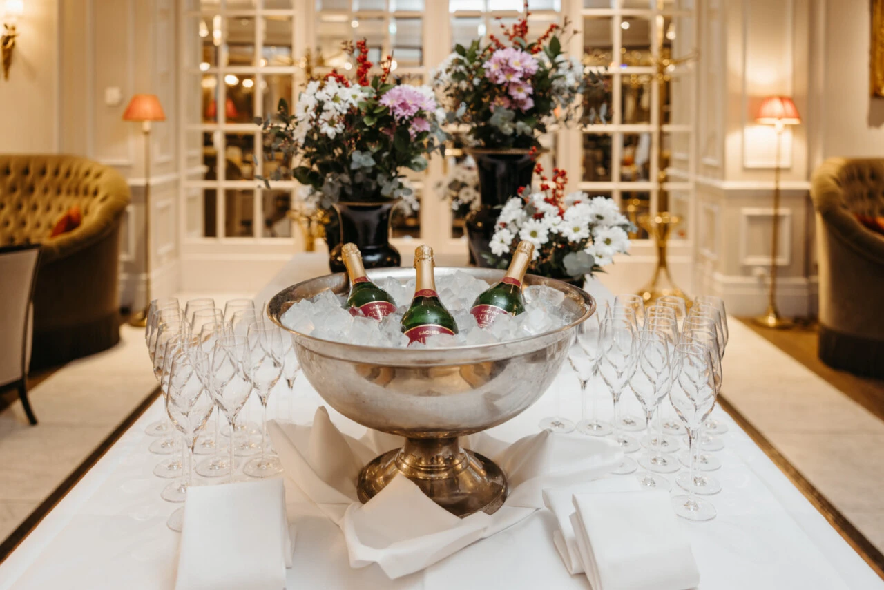 Champagne reception at Hotel Sacher Salzburg with bottles on ice, crystal glasses and elegant floral arrangements for private events and celebrations.
